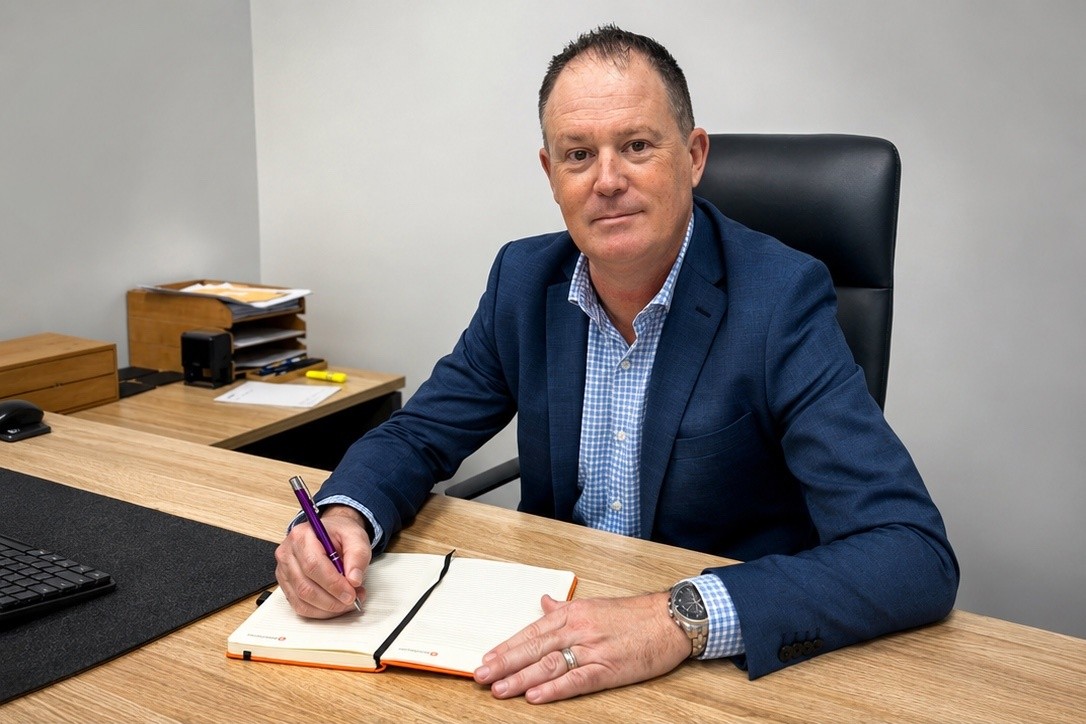 Andrew Newburn writing in a notebook at his desk in the Newburn Wealth Advisory office