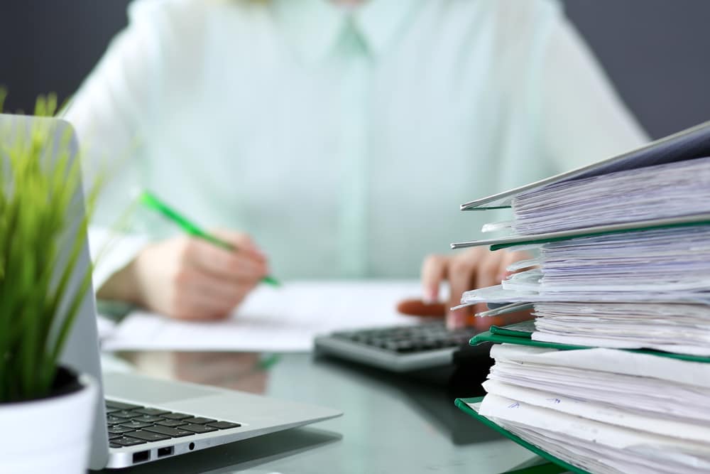 Adviser working through paperwork and a calculator at a desk during a Hunter region financial planning session
