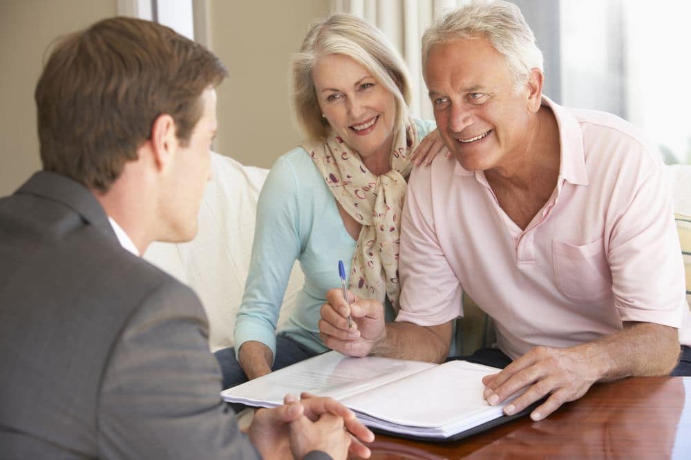Two older women sitting together while writing notes on their retirement planning documents